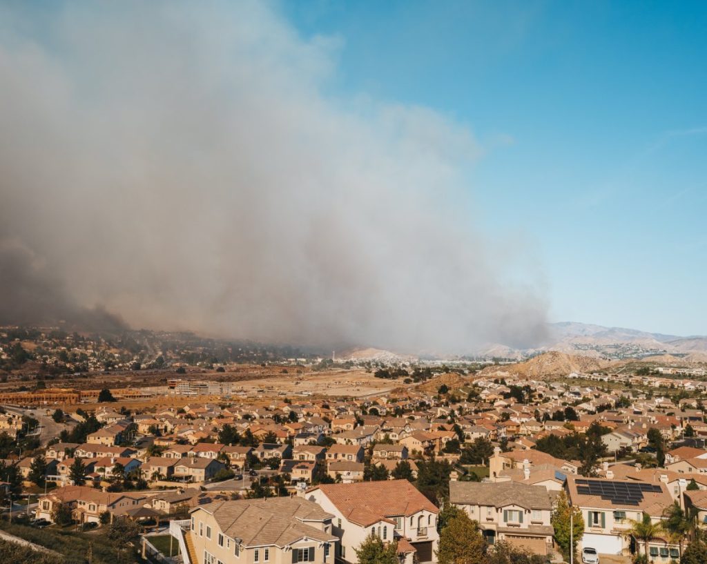 A California suburban neighborhood with smoke from a wildfire in the distance.